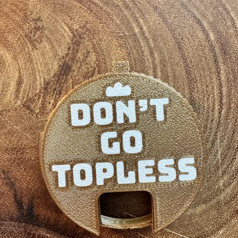A gold Top Block with the line Don't go topless in white, on a wood board