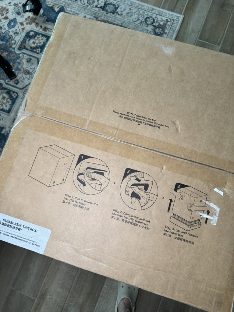 The top of the printer's sealed shipping box, with the steps for opening it from the bottom printed on it
